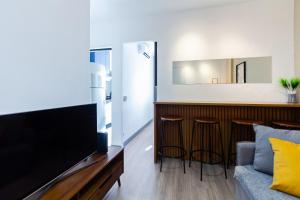 a living room with a tv and two bar stools at Apto 1 quarto, Centro, Cambuí, Guanabara, 1 vaga garagem, prox. a mercado, academia, hospital in Campinas