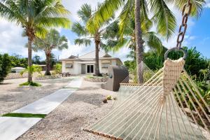a hammock in front of a house with palm trees at The Mastic Sunnyhill Cottage in North Side