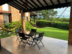 a patio with a table and chairs and a hammock at Alojamiento Rural Majapai in Quimbaya