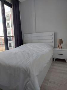 ein weißes Bett in einem weißen Schlafzimmer mit einem Fenster in der Unterkunft Comfort and Peace in a Luxury Residence! in Antalya
