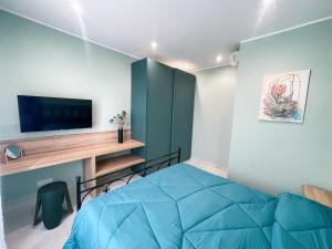 1 dormitorio con 1 cama azul y TV en Dolce Apartments Albano, en Albano Laziale
