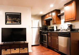 a kitchen with wooden cabinets and a television on a table at 1 Bed Apt - Amazing Location 1 Block to Carson St in Pittsburgh +6 photos