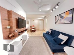 uma sala de estar com um sofá azul e uma televisão em Excelente Apartamento no Leblon 02 quadras da praia em prédio com piscina, sauna e academia no Rio de Janeiro
