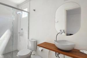 a bathroom with a sink and a toilet and a mirror at Morada do Sol - Pé na areia! in Florianópolis