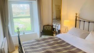 een slaapkamer met een bed, een raam en een stoel bij Park side Cottage, Number 2, The Morays in Blackford