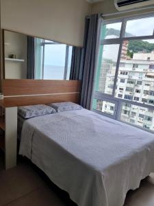 a bedroom with a bed and a large window at COPACABANA RIO PRAIA 18 in Rio de Janeiro