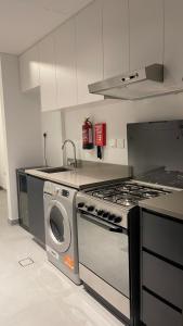 a kitchen with a stove and a washing machine at Al jada / Reef 4 in Sharjah