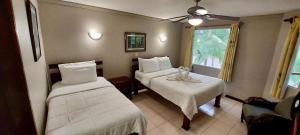 a hotel room with two beds and a window at Lovely Condo (8 people): Pools, Tennis Courts, BBQ in Manuel Antonio