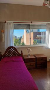 a bedroom with a purple bed and a large window at Monte Grande Centrico in Monte Grande