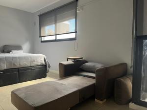 ein Schlafzimmer mit einem Sofa, einem Bett und einem Fenster in der Unterkunft Premium Apartment Rosario - Joan Miró in Rosario