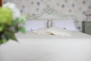 Una cama con sábanas blancas y almohadas en un dormitorio en SALGE b&b RESIDENZA DI CHARME, en Colonnella
