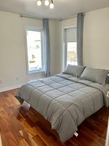 a large bed in a room with two windows at 3BR House 6 Guests Near Water in Laval