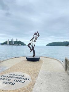 a statue of a person standing in front of a body of water at Pé na Areia Praia do Gonzaguinha in São Vicente