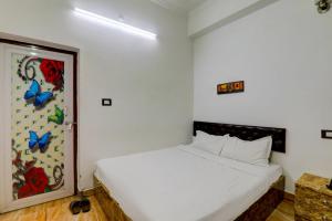 a bedroom with a white bed with a painting of butterflies at OYO Xpress Home in Lucknow