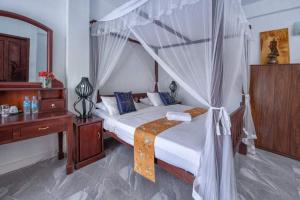 1 dormitorio con cama con dosel y escritorio de madera en The Richmond House Kandy en Kandy