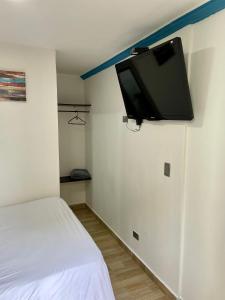 Zimmer mit einem Bett und einem TV an der Wand in der Unterkunft Habitación de descanso con aire acondicionado in Villavicencio