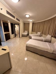 Habitación de hotel con 2 camas y sofá en ALBILAD ROYA HOTEL en Makkah