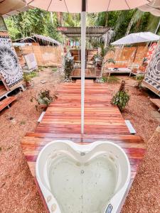 a heart shaped bath tub on a wooden walkway with an umbrella at Nomadic Surf Camp in Uvita