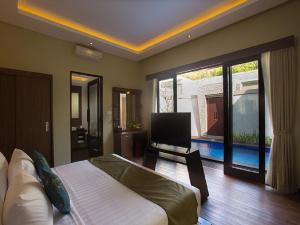 Un dormitorio con una cama y un televisor. en Buana Bali Villas & Spa, en Jimbaran