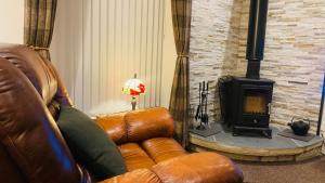 a living room with a leather couch and a fireplace at Park side Cottage, Number 2, The Morays in Blackford