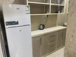 a white refrigerator in a kitchen with wooden cabinets at شقق أجياد السد in Mecca