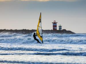 een man is aan het windsurfen in de oceaan met een zeil bij De Kleine Regentes in Den Haag