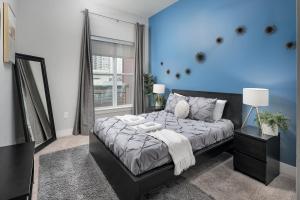 Trifecta Luxury Serviced Apartment in Uptown CLT في تشارلوت: غرفة نوم بسرير كبير وجدار ازرق