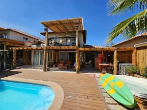 a house with a pool and a deck with a surfboard at RÚSTICA VIZCACHAS in Puente Alto