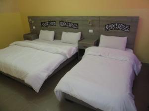 Cette chambre comprend 2 lits avec des draps blancs. dans l'établissement Best hotel aqaba, à Aqaba