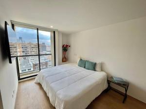 ein Schlafzimmer mit einem großen Bett und einem großen Fenster in der Unterkunft SkyLine Mountains Sauna Gym Luxury Apto in Bogotá