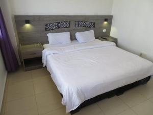 Best hotel aqaba في العقبة: غرفة نوم بسرير كبير عليها شراشف ووسائد بيضاء