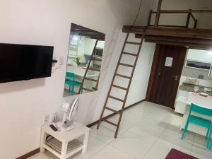 a living room with a television and a ladder at Apartamento mezanino Villas do pratagy in Maceió
