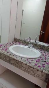 a bathroom counter with a sink with flowers on it at Apartamento mezanino Villas do pratagy in Maceió