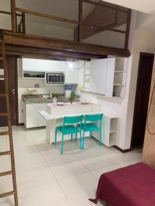 a kitchen with a table and two blue chairs at Apartamento mezanino Villas do pratagy in Maceió