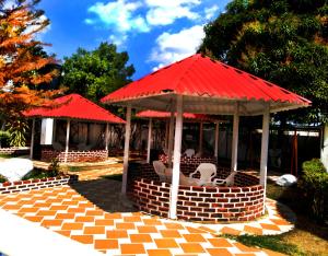 a gazebo with red roofs and white chairs at CENTRO VACACIONAL & HOTEL CAMPESTRE LAGO CENTER in Aguazul