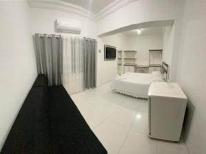 a white room with a bed and a television at Grande Hotel in Paranavaí