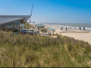 a view of a beach with a building and the ocean at Luxe Stacaravan Albatros - 51 in Bredene