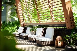 a row of white chairs sitting under a pergola at 1 Hotel Hanalei Bay in Princeville