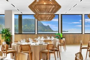 a dining room with tables and chairs and windows at 1 Hotel Hanalei Bay in Princeville