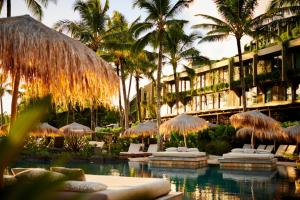 a resort with a pool with umbrellas and palm trees at 1 Hotel Hanalei Bay in Princeville