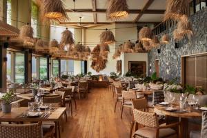 um restaurante com mesas e cadeiras de madeira e janelas em 1 Hotel Hanalei Bay em Princeville