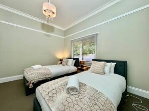 a bedroom with two beds and a chandelier at Maple Grove in Katoomba