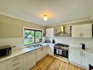 a large kitchen with white cabinets and a window at Maple Grove in Katoomba