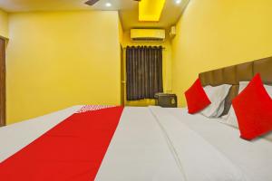 OYO Flagship Peppy Guest House في كالانغيُت: غرفة نوم بسرير كبير ومخدات حمراء وبيضاء