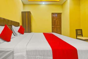 een slaapkamer met een groot wit bed met rode kussens bij OYO Flagship Peppy Guest House in Calangute