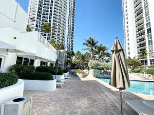 an umbrella next to a swimming pool with buildings at 21st Floor Luxury Suite at Trump Int Resort in Miami Beach