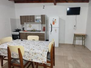 cocina con mesa y nevera blanca en Departamentos teuli en Puerto San Julián