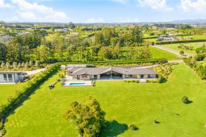 an aerial view of a large green field with a house at Luxury Modern 3-BDR Oasis in Kumeu