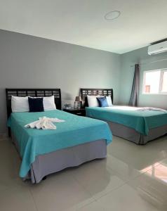 a bedroom with two beds with blue sheets at Hotel Boutique Los Pinos in Santa Rosa de Copán