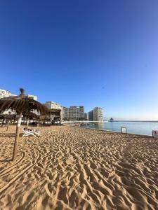 a sandy beach with an umbrella and the ocean at Lagunas del mar in La Serena